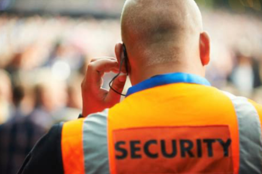 Security guard wearing high-visibility jacket and earpiece providing 14-hour manned guarding services